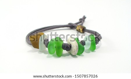 Beach jewelry - bracelet made of beach pebbles, sea glass and green cord on white background. Handmade gift concept. Royalty-Free Stock Photo #1507857026