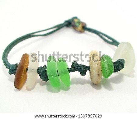 Beach jewelry - bracelet made of beach pebbles, sea glass and leather cord on white background. Handmade gift concept. Royalty-Free Stock Photo #1507857029