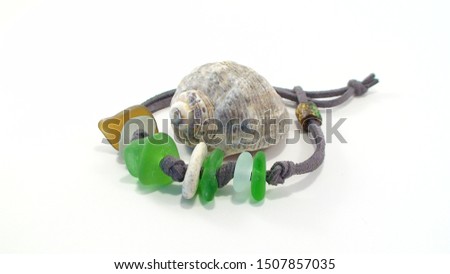 Beach jewelry - bracelet made of beach pebbles, sea glass lies around the sea shell on white background. Handmade gift. Royalty-Free Stock Photo #1507857035