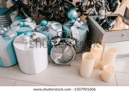 Decorated Christmas interior. Tree with gifts boxes, clock, candles in a white room. Decor. Happy New Year and Merry Christmas. The concept of winter holiday.