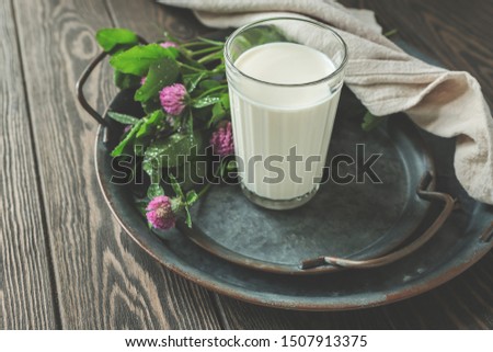 glass of milk and clover on a dark wooden table
