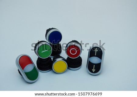 Push-button type electrical switch for panel mounting. White background. Switches and buttons start-stop red green yellow blue. Up and down black button.