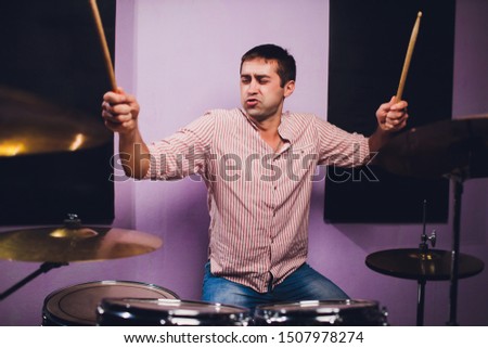 Young man behind drum-type installation in a professional recording studio.