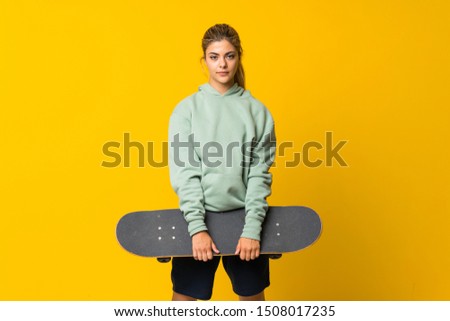 Blonde teenager skater girl over isolated yellow background