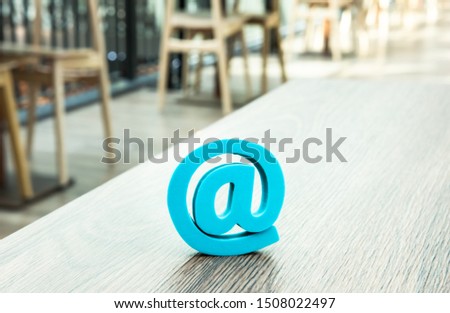 Trendy mint blue at sign at desktop in cafe. Email symbol concept. 
