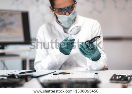 Digital Forensic Science. Police Forensic Analyst Examining Confiscated Mobile Phone. Royalty-Free Stock Photo #1508063450