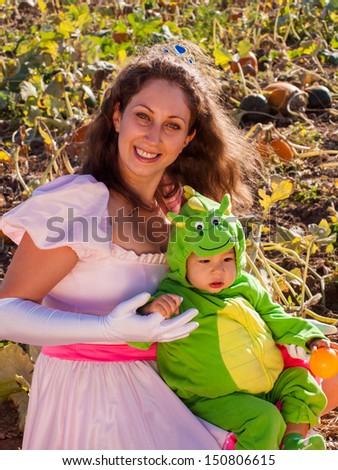 Toddler and his mother dressed up in cute costumes at the pumpkin patch.