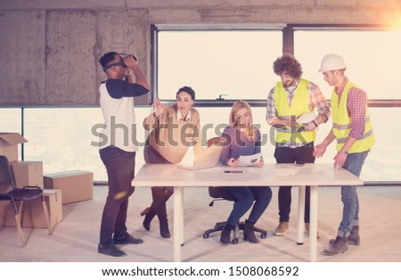 young multiethnic business team checking documents and business workflow on construction site using the virtual reality headset and laptop computer with sunlight through the windows during