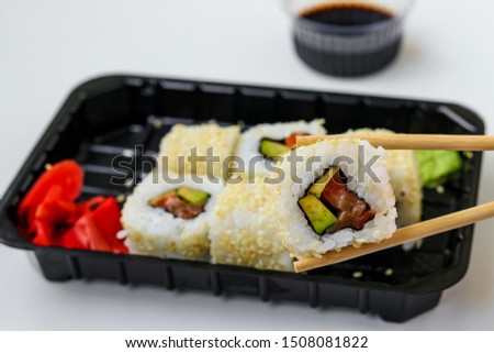 Syake rolls in a set of 6 pieces in a black box, with ginger, wasabi and soy sauce, fast food, horizontal orientation