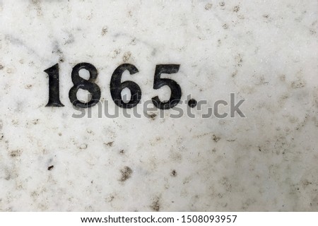 The year 1865 carved in stone and painted in black – a detail of an inscription produced that year
