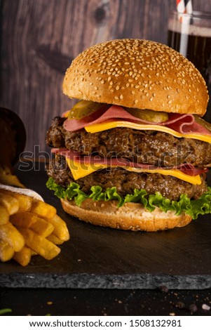 Hamburger with french fries and cola on stone table with wooden background