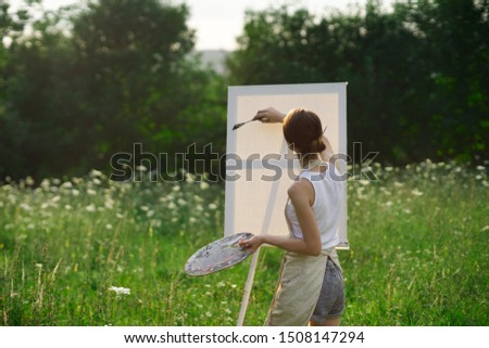woman artist paints a brush painting nature