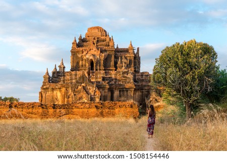 Horizontal picture of tourist woman looking to the ruins of Thitsarwadi Temple during sunset time in Bagan, Myanmar