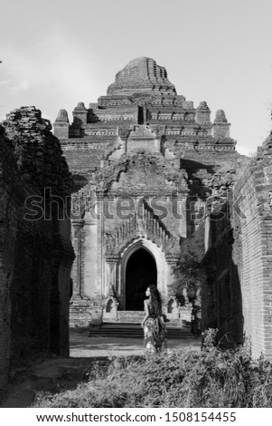 Black and white picture of young woman posing in front of the huge Dhammayan Gyi Temple, a landmark of Bagan, Myanmar
