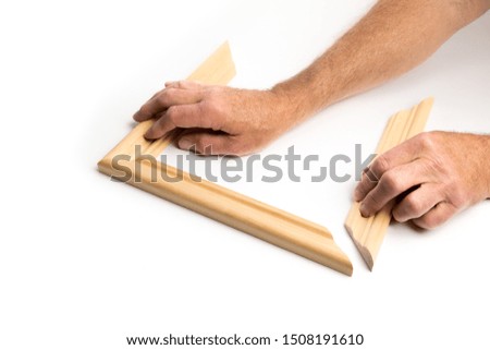 worker holding angle cut wood to make a picture frame isolated on white