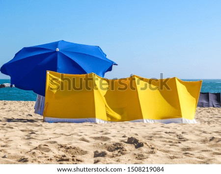 Blue sun umbrella on the beach. Sun and wind protection on the beach at summer.