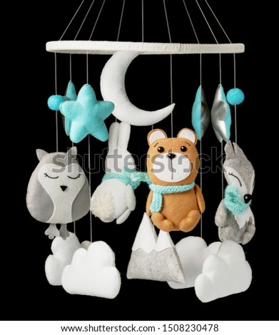Colorful and eco-friendly children's mobile from felt for children. It consists of bear, fox, owl, rabbit, mountain, stars, clouds and balloons toys. Handmade on black background.