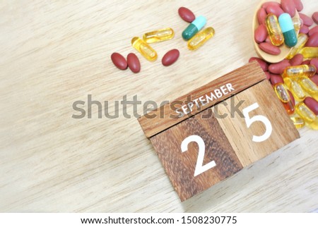Wooden calendar on September 25 and medicine on the wooden background, the concept of World Pharmacist Day