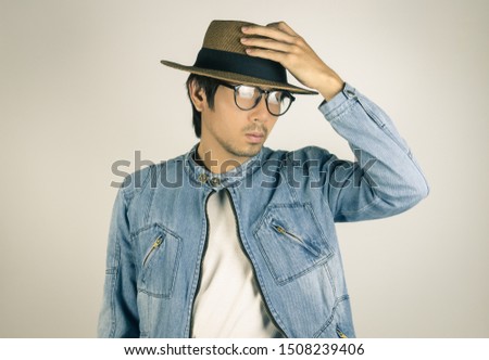Young Asian Man in Jeans Jacket or Denim Jacket Wear Eyeglasses and Touching Hat. Denim or Jeans Jacket Men Fashion on Gray Background