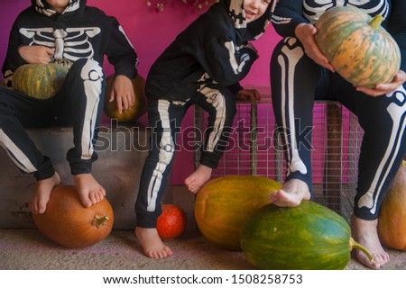 elderly witch grandmother is sitting in barn with her grandchildren. Children and old woman are dressed in skeleton costumes. Halloween eve with pumpkins in hands