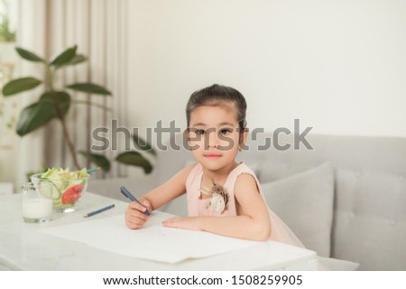Little girl drawing picture at table with painting tools indoors