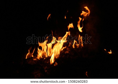 The flame is burning with a scattering heat energy on a black background.
