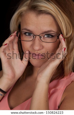 A close up of a woman holding on to her glasses with a serious expression on her face.