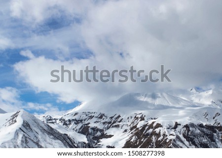 Snow-capped mountain peaks, white clouds.