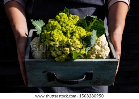 woman holds a box with cauliflower