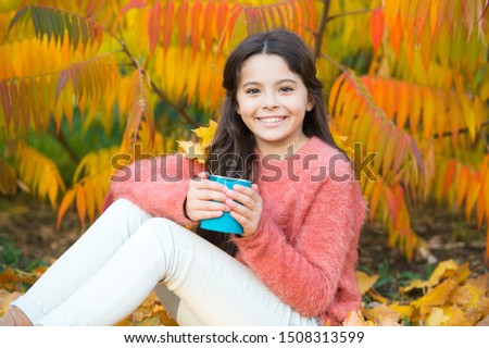 Cozy ideas for autumn picnic. Girl happy kid with mug in autumn park colorful foliage background. Hot beverage. Health care. Little child enjoy autumn hot drink. Little child relax at autumn tree.