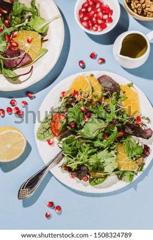 Flatlay of two citrus salad plates  with pomegranate seeds, nut and olive oil on blue background