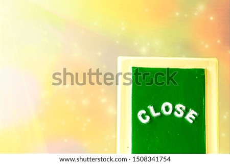 Close up of a green ,yellow with white "CLOSE" chalkboard sign leaning against bright, colorful with sparkle background.