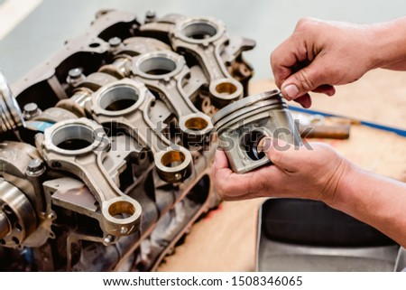 Pistons in the mechanic's hands that are being cleaned during the overhaul process is a maintenance in the car garage. Royalty-Free Stock Photo #1508346065