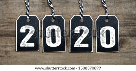 Black hang tags with 2020 on wooden background