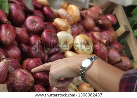 A buyer chooses from a market display of fresh red, white and purple onions. 2938