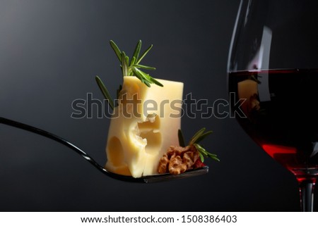 Maasdam cheese with walnuts, rosemary and red wine on a black background. Copy space.