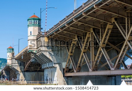 Wide transportation Burnside drawbridge over the Willamette River in down town of Portland Oregon with towers on concrete supports with hoisting mechanisms for raising the central part of the bridge Royalty-Free Stock Photo #1508414723
