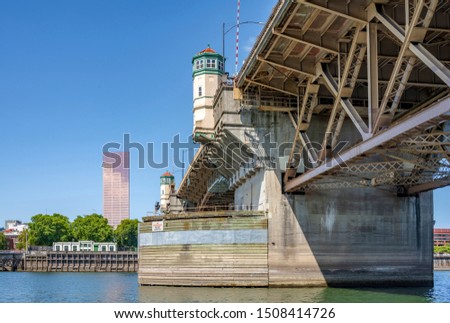 Wide transportation Burnside drawbridge over the Willamette River in down town of Portland Oregon with towers on concrete supports with hoisting mechanisms for raising the central part of the bridge Royalty-Free Stock Photo #1508414726