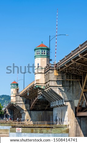 Wide truss Burnside drawbridge over the Willamette River in down town of Portland Oregon with towers on concrete supports with hoisting mechanisms for raising the central part of the bridge  Royalty-Free Stock Photo #1508414741
