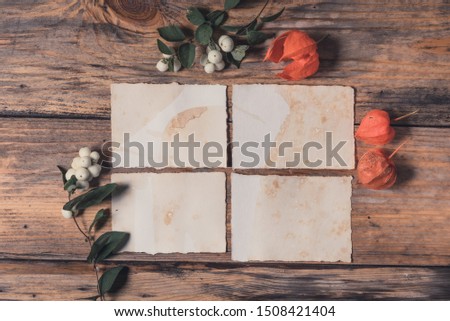 Mockup card with winter cherries, branches on wooden background . Flat lay,top view. Wedding invitation card with environment and details. Blank card on rustic wood background for creative work design