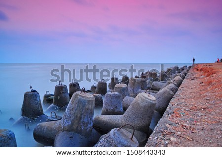 
the beach with a breakwater with a beautiful sunset background
