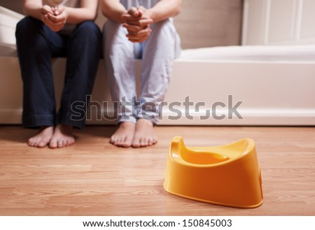 Young parents are sitting on the bed and thinking how to teach kid to use children's pot. Shallow depth of field. Royalty-Free Stock Photo #150845003