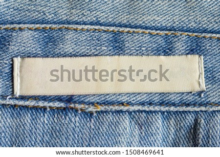 Blank white laundry care clothing label on denim jeans texture background