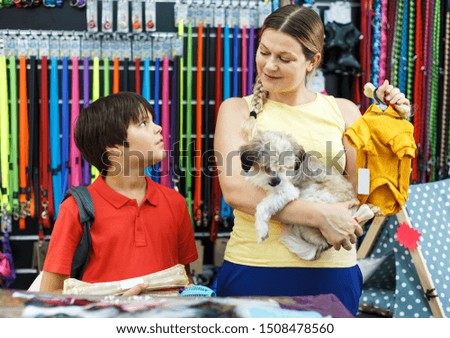 Careful preteen boy with mother visiting pet shop in search of clothes for their dog