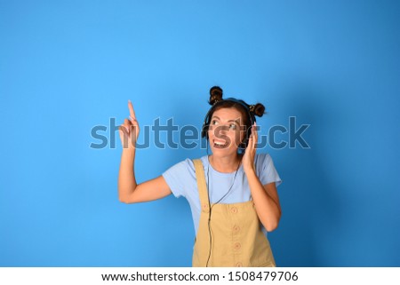 woman with headphones pointing at free place on a blue background