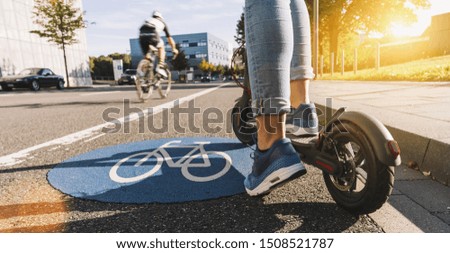 Close up of woman start to riding a electric scooter or kick scooter at cityscape on a Bicycle road sign way Royalty-Free Stock Photo #1508521787