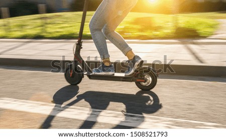 woman riding black electric kick scooter at cityscape at summer, motion blur Royalty-Free Stock Photo #1508521793