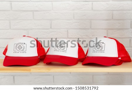 Red and white caps with logo on wooden shelf in shop