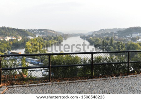 Iron fence on top of the wall of the Vysehrad (Czech: Vyšehrad) fort in Prague, Czech Republic. Slightly blurred panorama over the valley of the Vltava river behind the fence. Quiet summer evening.