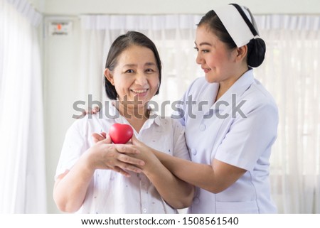 Nurse and Asian elderly woman holding heart red model on hands together,good health good life,Senior healthy and taking care concept